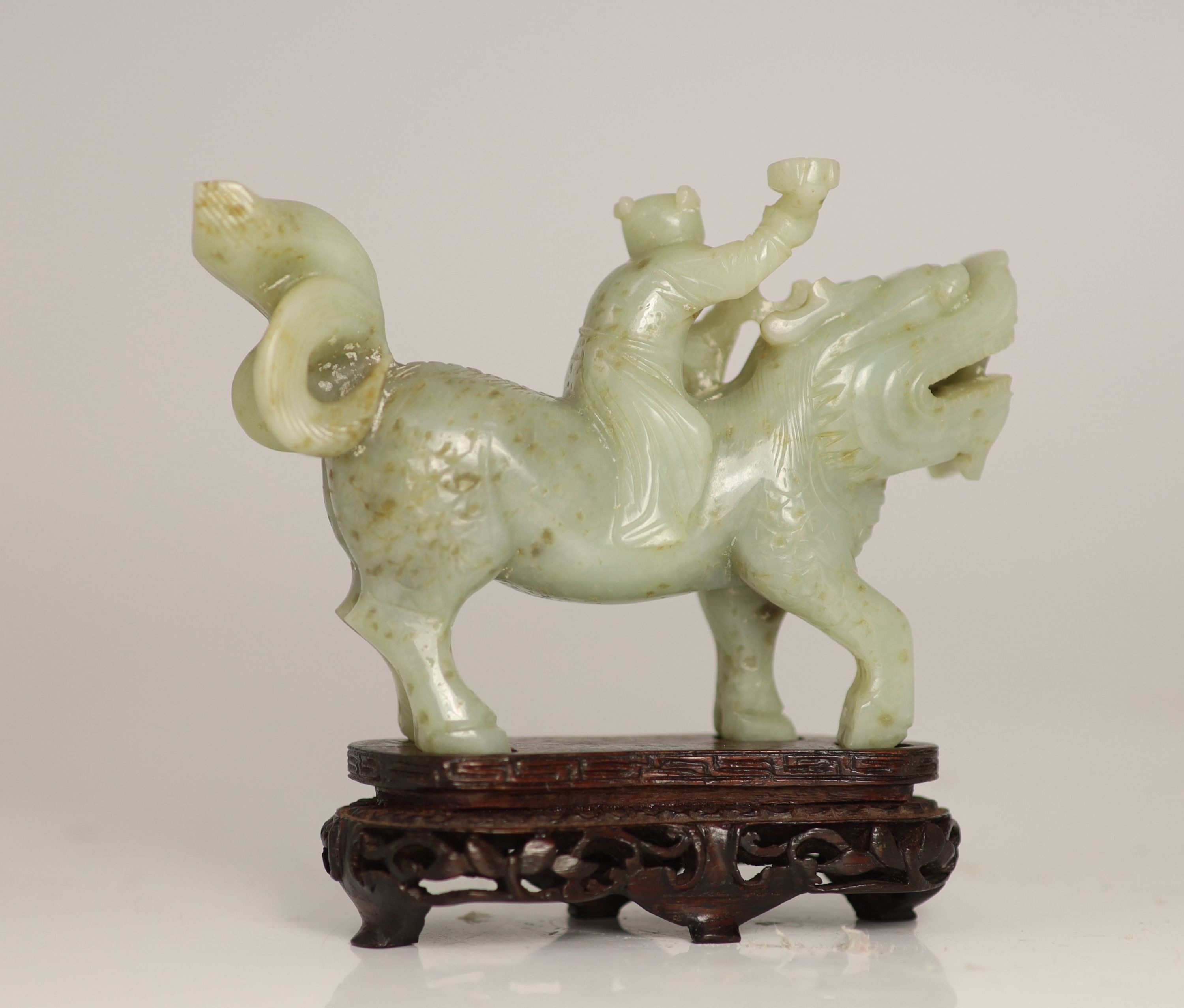 A Chinese pale celadon-grey jade group of a boy riding a qilin, 17th/18th century, 13.5cm long, wood stand
